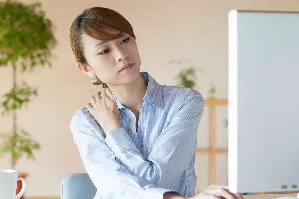 デスク仕事で肩こりに悩む女性